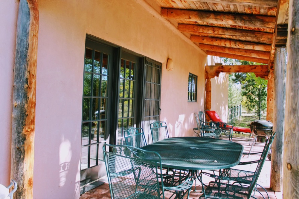 A covered adobe patio with seating, set up for gathering